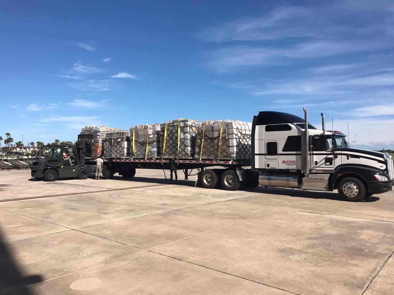 Forklift loading pallets onto King Transport flatbed truck